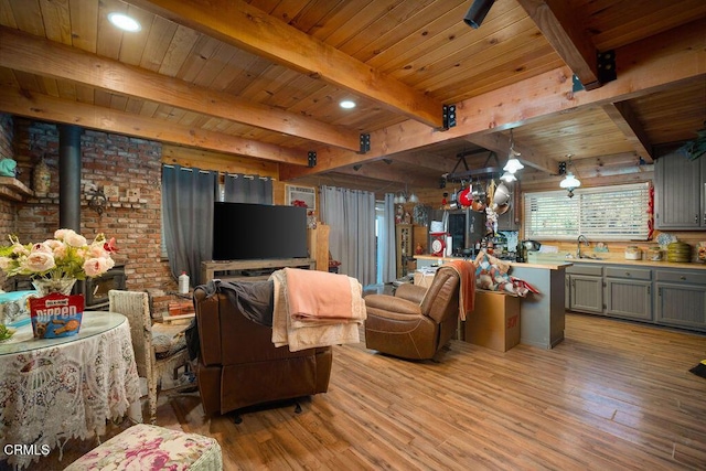 living area featuring light wood-type flooring, a wood stove, beam ceiling, and wooden ceiling