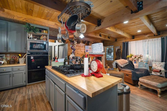 kitchen with light wood-type flooring, wood counters, gray cabinetry, and stainless steel appliances