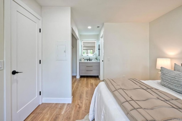 bedroom featuring a sink, ensuite bath, light wood-style floors, baseboards, and visible vents