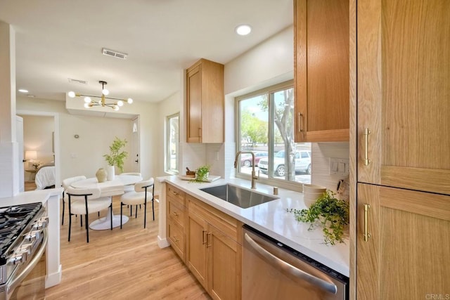 kitchen featuring visible vents, light wood-type flooring, a sink, light countertops, and stainless steel appliances