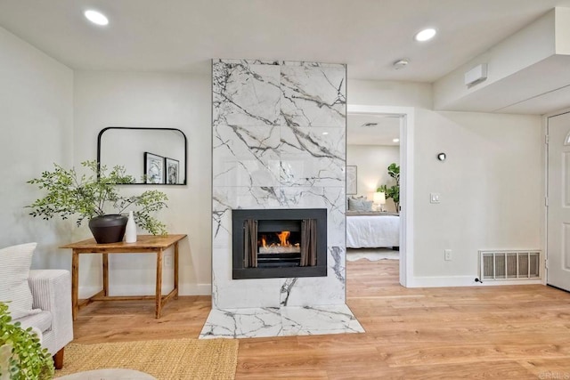 interior space featuring a fireplace, recessed lighting, baseboards, wood finished floors, and visible vents