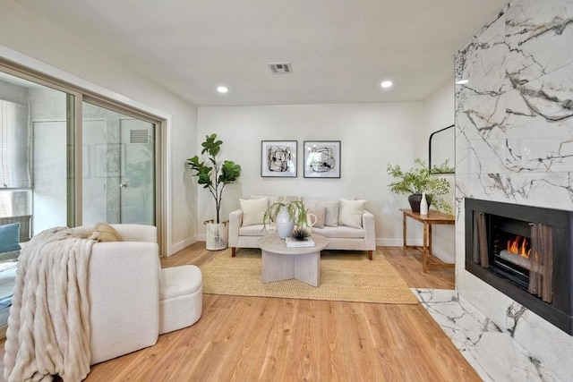 living area with a high end fireplace, recessed lighting, wood finished floors, and visible vents