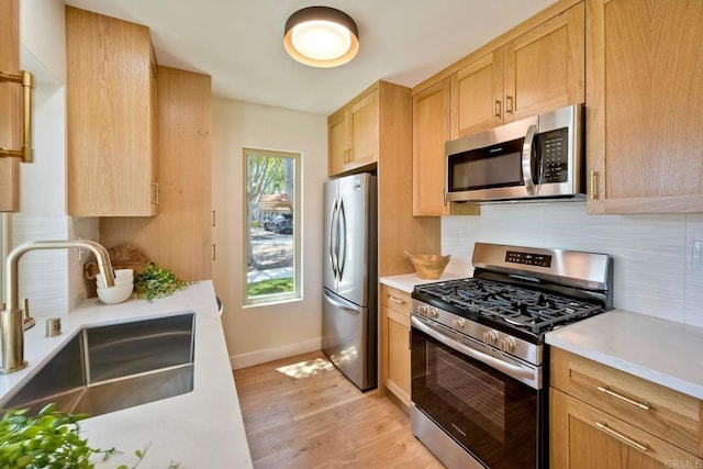 kitchen with light countertops, stainless steel appliances, a sink, and light wood-style flooring