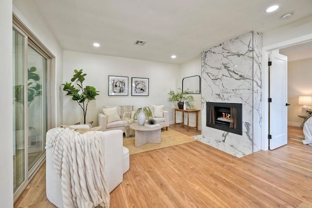 living room with recessed lighting, visible vents, wood finished floors, and a fireplace