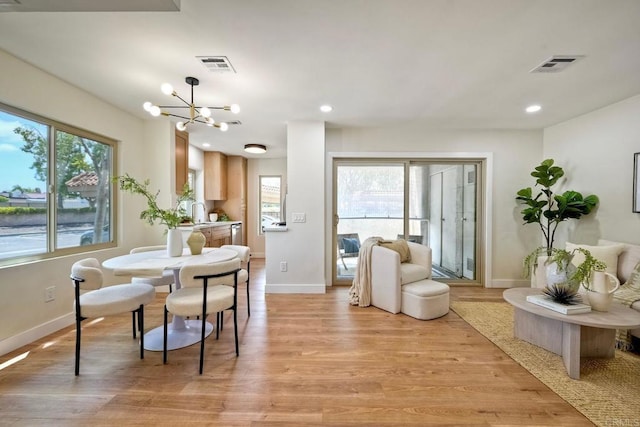 interior space with baseboards, visible vents, an inviting chandelier, and light wood-type flooring