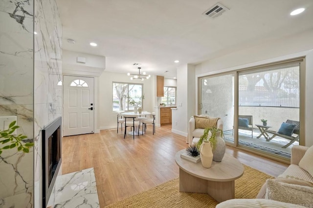 living room featuring visible vents, baseboards, light wood finished floors, a chandelier, and recessed lighting