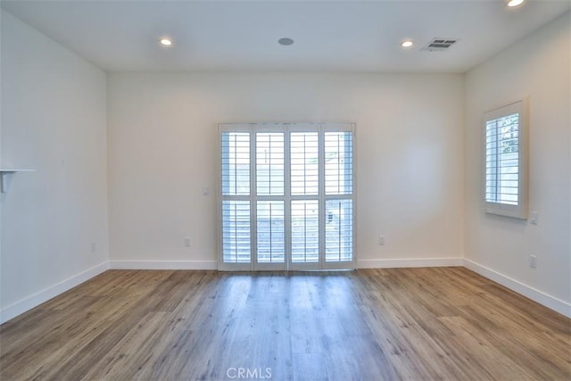 spare room with baseboards, recessed lighting, wood finished floors, and visible vents