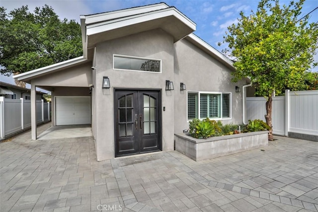 exterior space featuring french doors, fence, stucco siding, and driveway