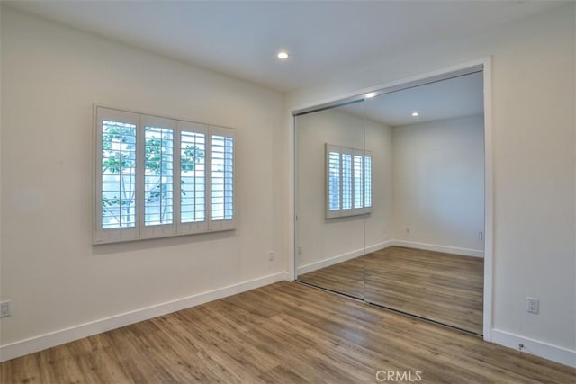 spare room featuring baseboards, recessed lighting, and wood finished floors