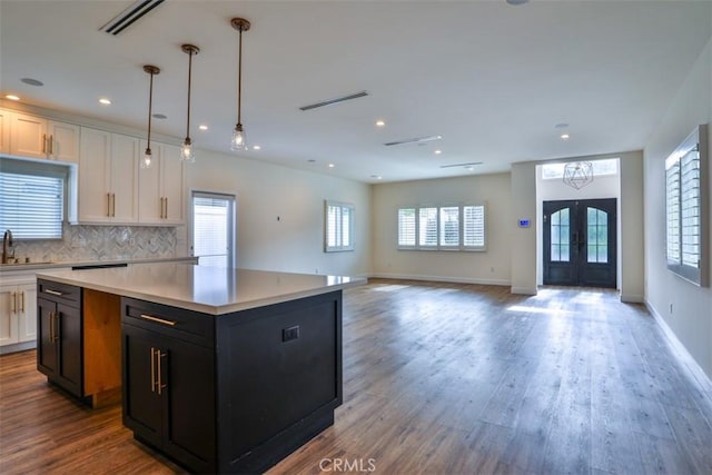 kitchen featuring a sink, light countertops, french doors, white cabinetry, and a kitchen island