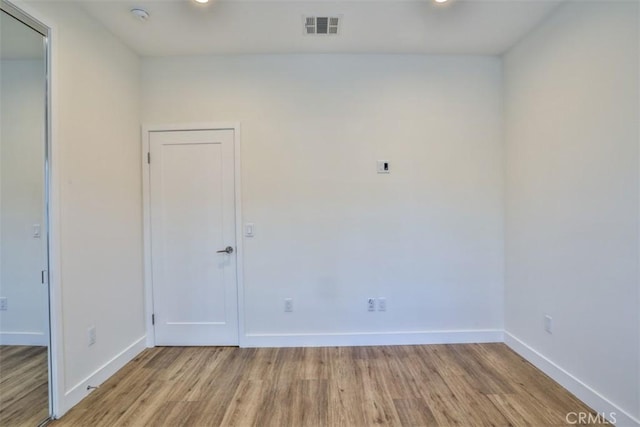 spare room featuring visible vents, light wood finished floors, and baseboards