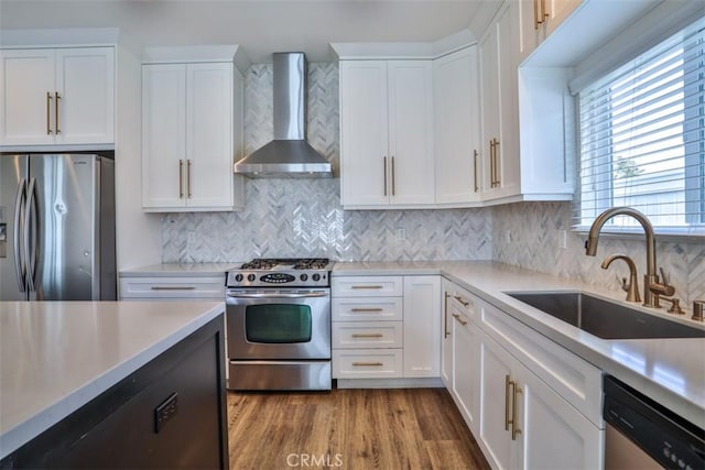 kitchen featuring a sink, appliances with stainless steel finishes, wall chimney exhaust hood, and light countertops