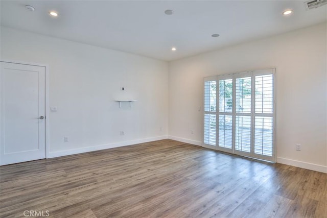 spare room with visible vents, recessed lighting, baseboards, and wood finished floors