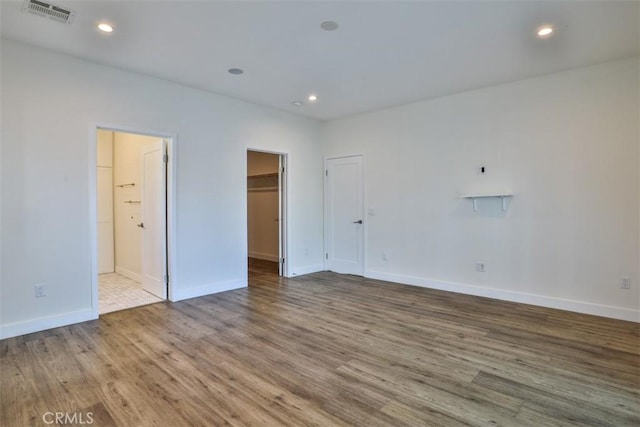 interior space with visible vents, wood finished floors, baseboards, ensuite bathroom, and a walk in closet