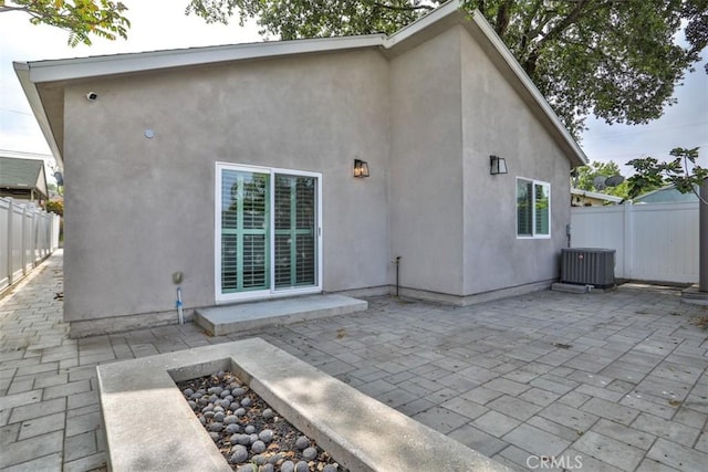 back of property with a patio, central AC unit, stucco siding, and fence