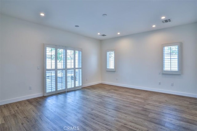 spare room with recessed lighting, plenty of natural light, and wood finished floors