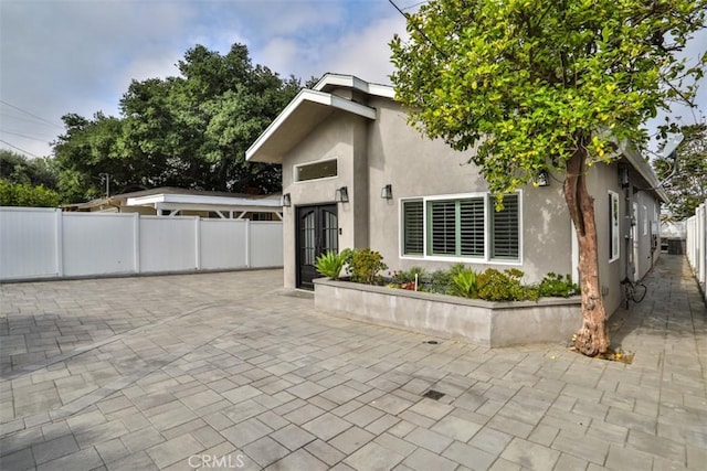 view of front of home with fence, a patio area, and stucco siding
