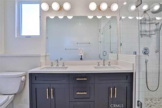 full bathroom with double vanity, a sink, a stall shower, and toilet