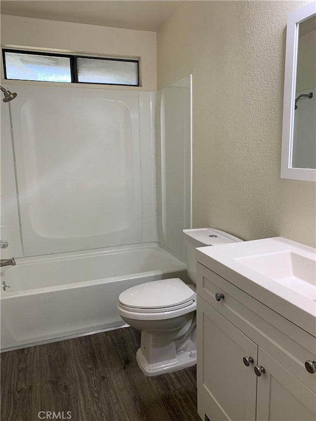 bathroom with toilet, washtub / shower combination, wood finished floors, and vanity