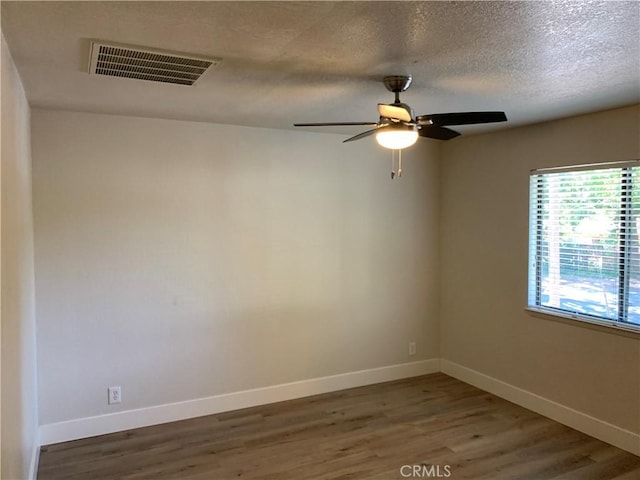empty room featuring baseboards, a ceiling fan, wood finished floors, and visible vents
