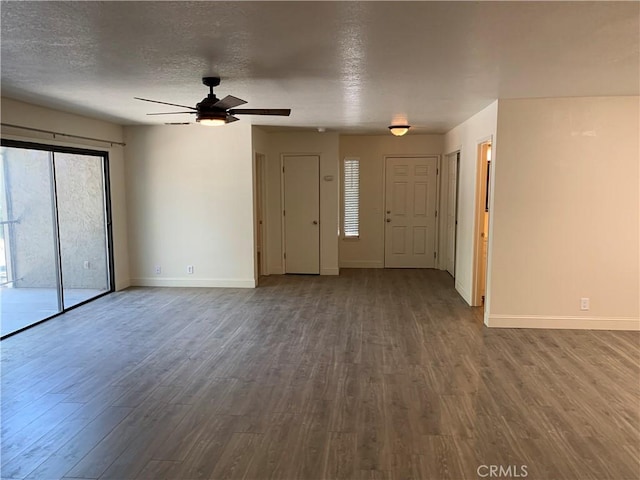 unfurnished living room with baseboards, ceiling fan, dark wood finished floors, and a textured ceiling