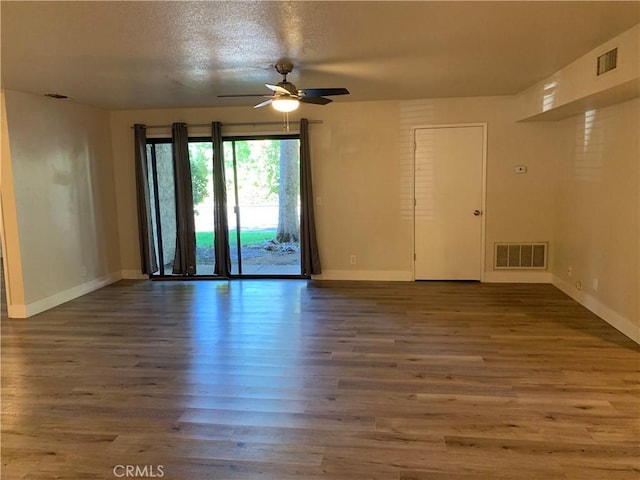 spare room featuring visible vents, a ceiling fan, baseboards, and wood finished floors