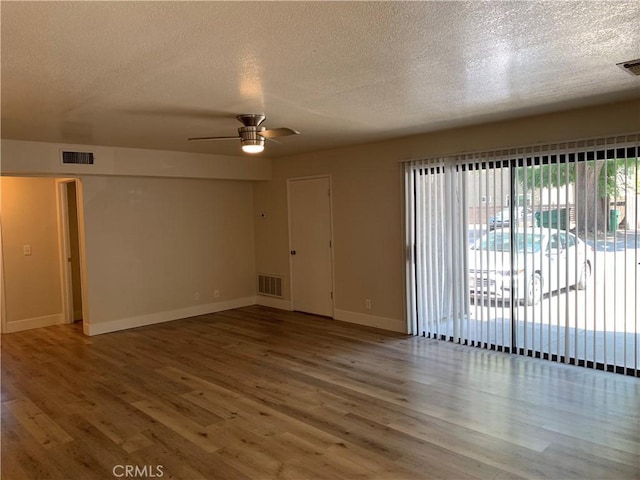 spare room featuring wood finished floors, a textured ceiling, and visible vents