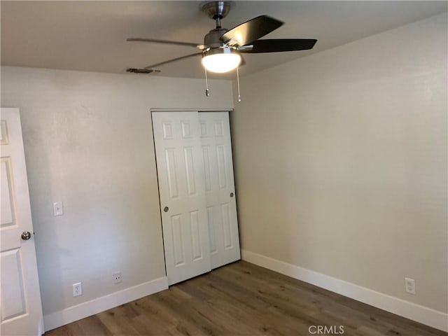 unfurnished bedroom with a ceiling fan, baseboards, wood finished floors, and a closet