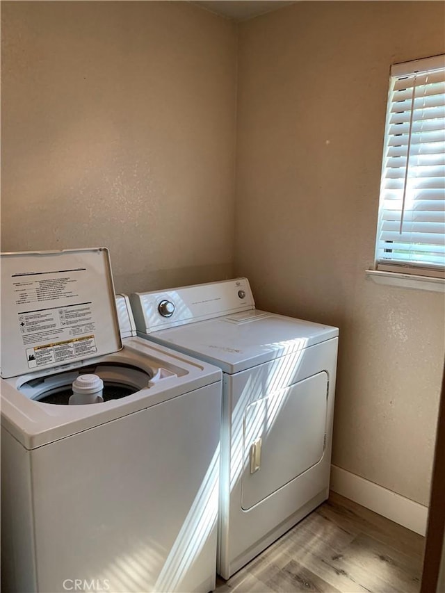 washroom with washer and dryer, laundry area, baseboards, and light wood-style floors