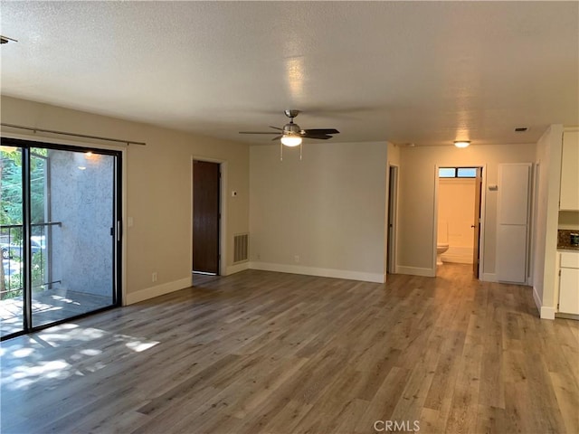 unfurnished living room with baseboards, ceiling fan, wood finished floors, and visible vents