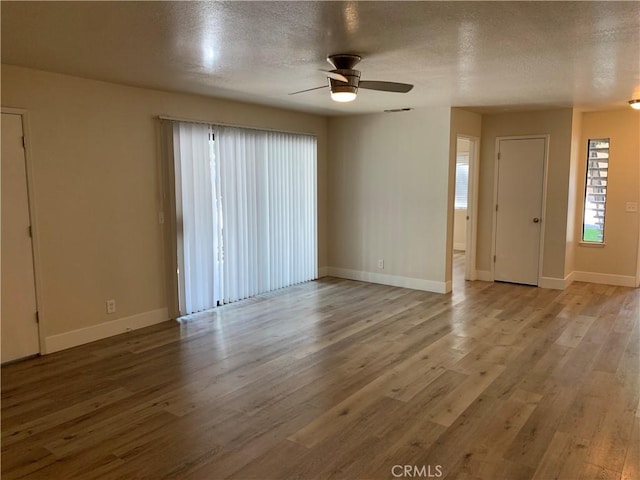 spare room featuring baseboards, ceiling fan, a textured ceiling, and wood finished floors