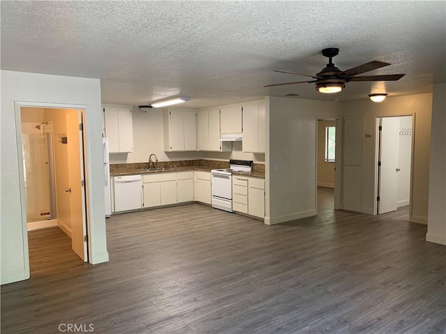 kitchen with dark countertops, white appliances, baseboards, a textured ceiling, and a sink