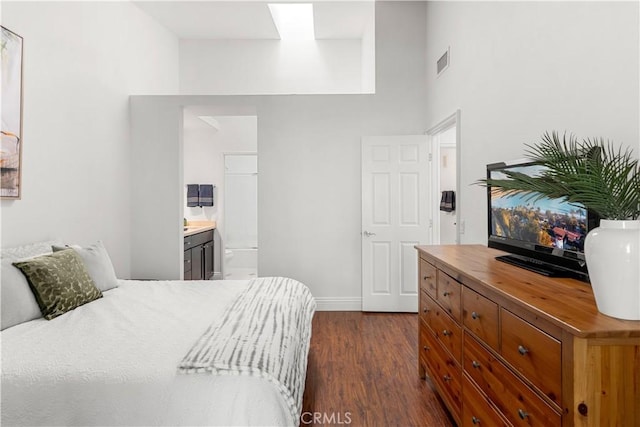 bedroom with visible vents, a towering ceiling, baseboards, dark wood-type flooring, and connected bathroom