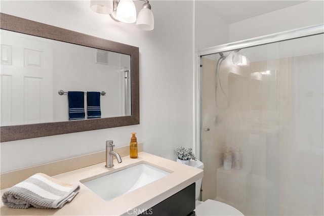 full bathroom featuring vanity, a shower stall, toilet, and visible vents