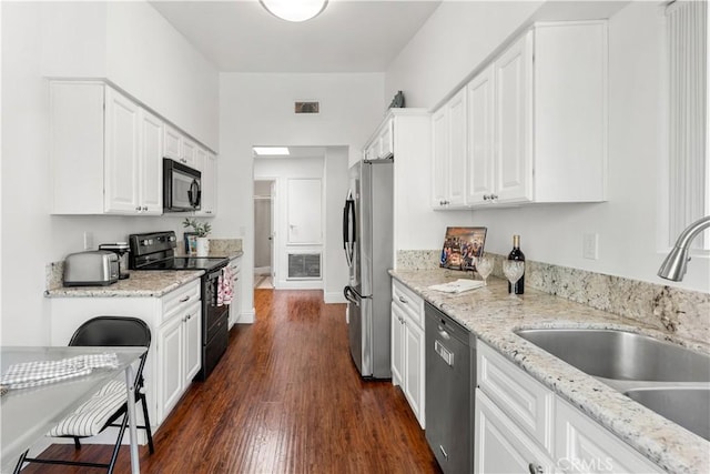 kitchen featuring visible vents, dark wood-type flooring, white cabinets, a sink, and black appliances