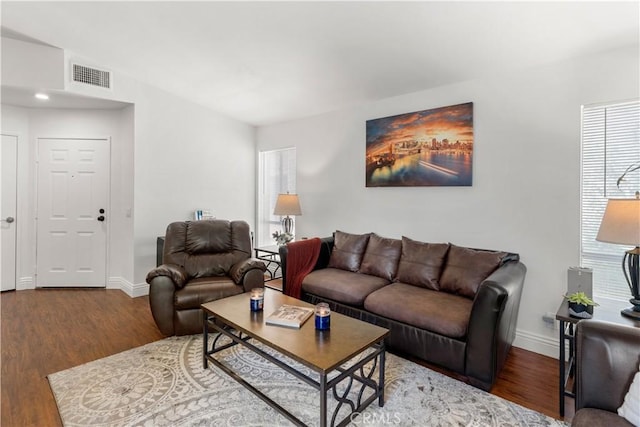 living room featuring visible vents, baseboards, wood finished floors, and a healthy amount of sunlight