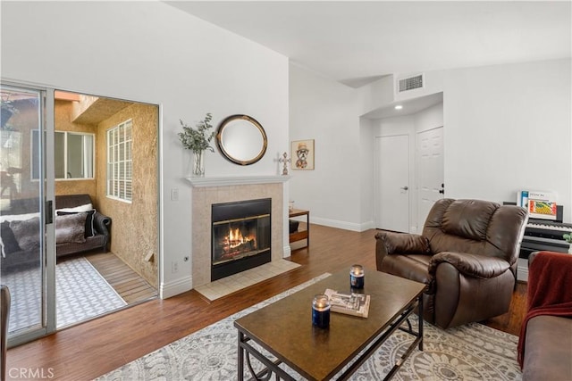 living area with baseboards, a fireplace, wood finished floors, and visible vents