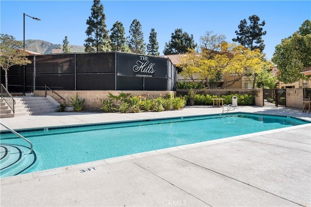 community pool featuring a patio, fence, and a mountain view