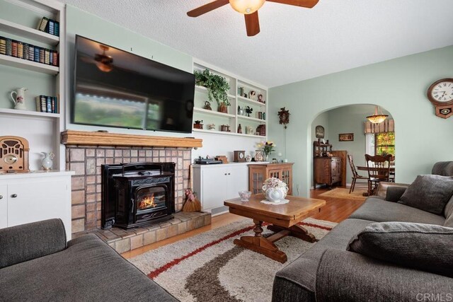 1704 Winterwarm Dr, Fallbrook, CA 92028 - living area with arched walkways, ceiling fan, wood finished floors, and a tiled fireplace