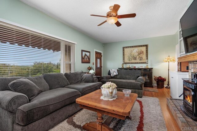 1704 Winterwarm Dr, Fallbrook, CA 92028 - living area featuring a ceiling fan, wood finished floors, a wood stove, and a textured ceiling