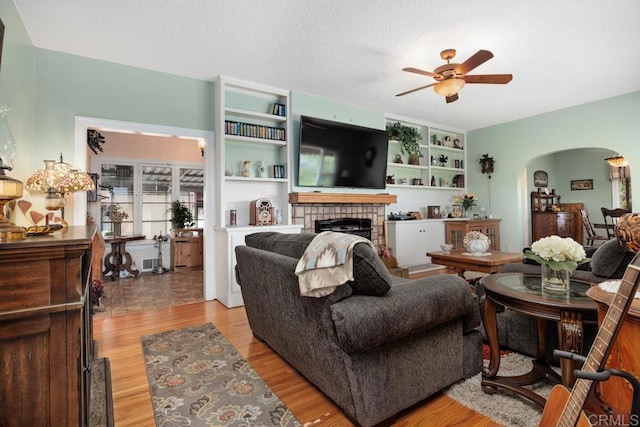 1704 Winterwarm Dr, Fallbrook, CA 92028 - living area featuring ceiling fan, arched walkways, a fireplace, and light wood-type flooring