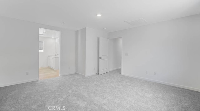 unfurnished bedroom featuring baseboards, recessed lighting, ensuite bath, and light carpet