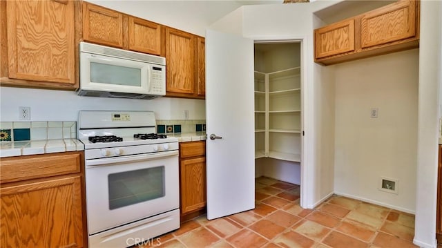 9630 El Mirador Blvd, Desert Hot Springs, CA 92240 - kitchen with tile counters, brown cabinetry, and white appliances