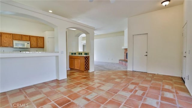 9630 El Mirador Blvd, Desert Hot Springs, CA 92240 - kitchen featuring brown cabinetry, white microwave, recessed lighting, light countertops, and arched walkways