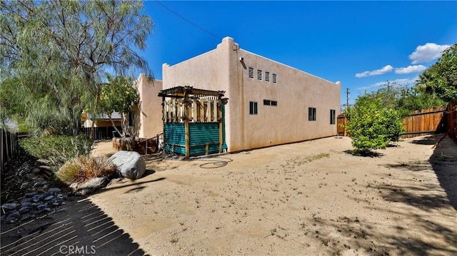 9630 El Mirador Blvd, Desert Hot Springs, CA 92240 - view of side of property with a pergola, stucco siding, and fence private yard