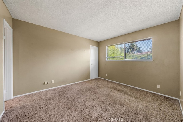 empty room with carpet floors, a textured ceiling, and baseboards