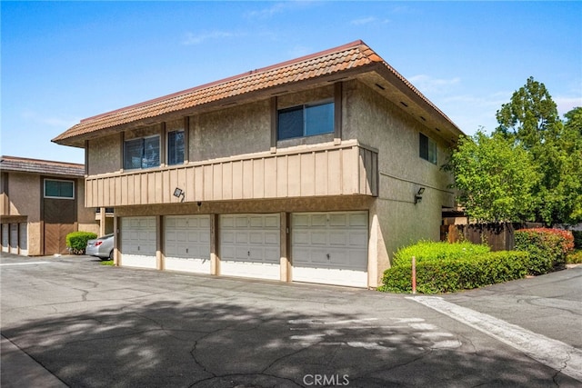 exterior space with a tiled roof, a garage, driveway, and stucco siding