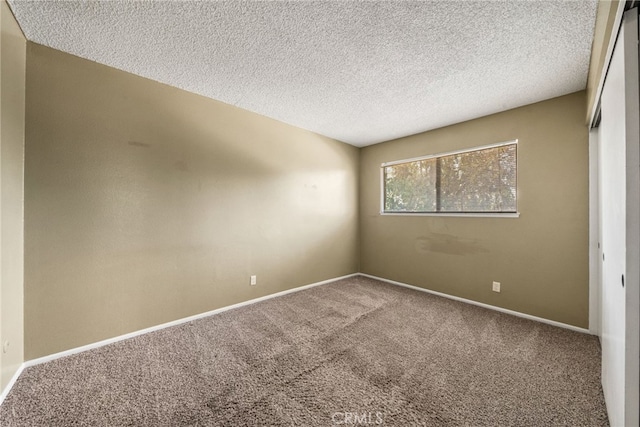 spare room featuring carpet floors, baseboards, and a textured ceiling