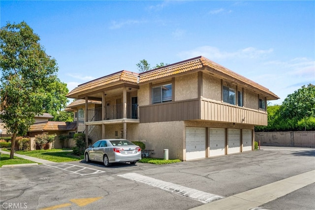 view of building exterior featuring a garage, uncovered parking, and fence