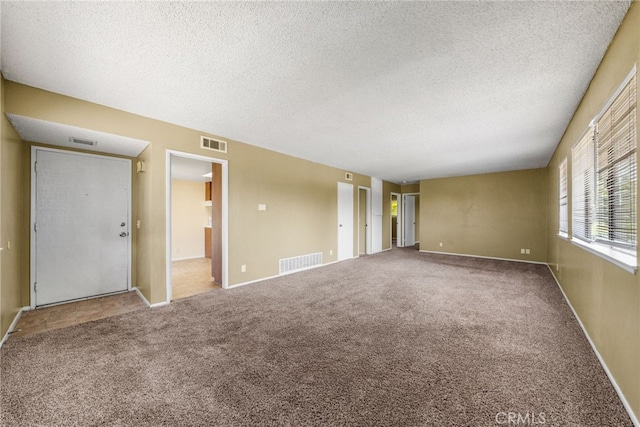unfurnished room with carpet floors, a textured ceiling, and visible vents